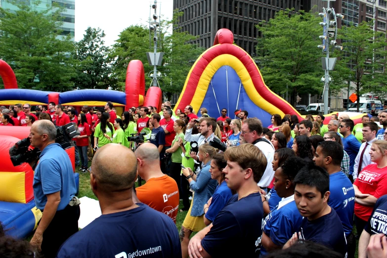 a large crowd in a park surrounded by people