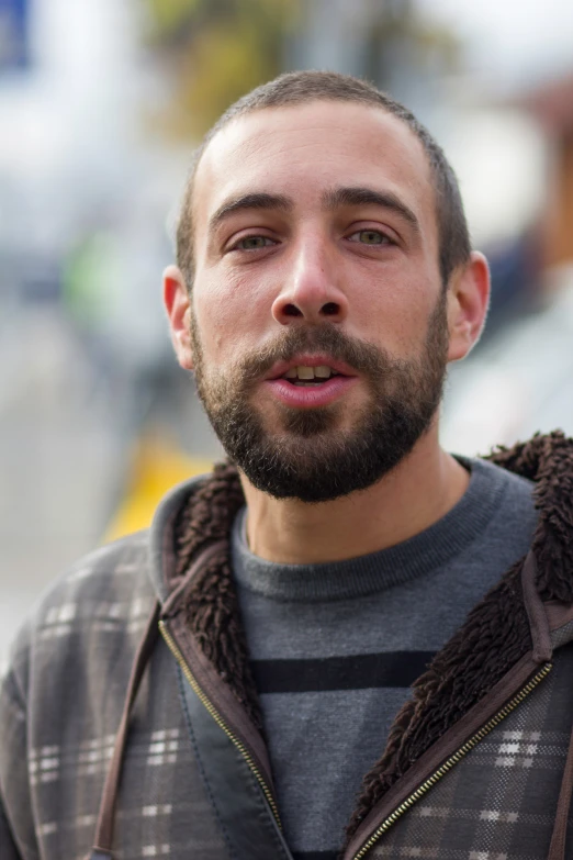 a man with a beard in a hoodie is looking at the camera