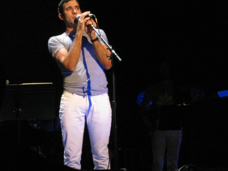 man holding microphone at microphone stand on stage