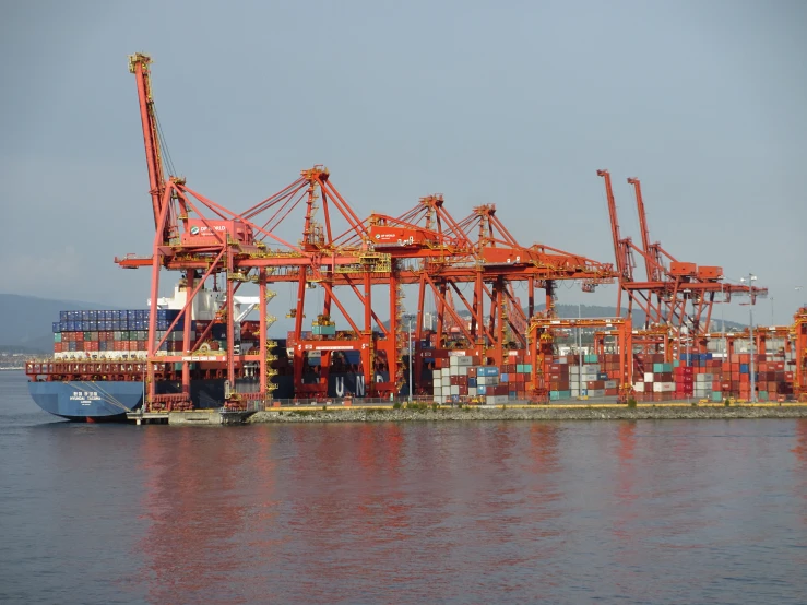 cranes and containers sit stacked on top of a body of water