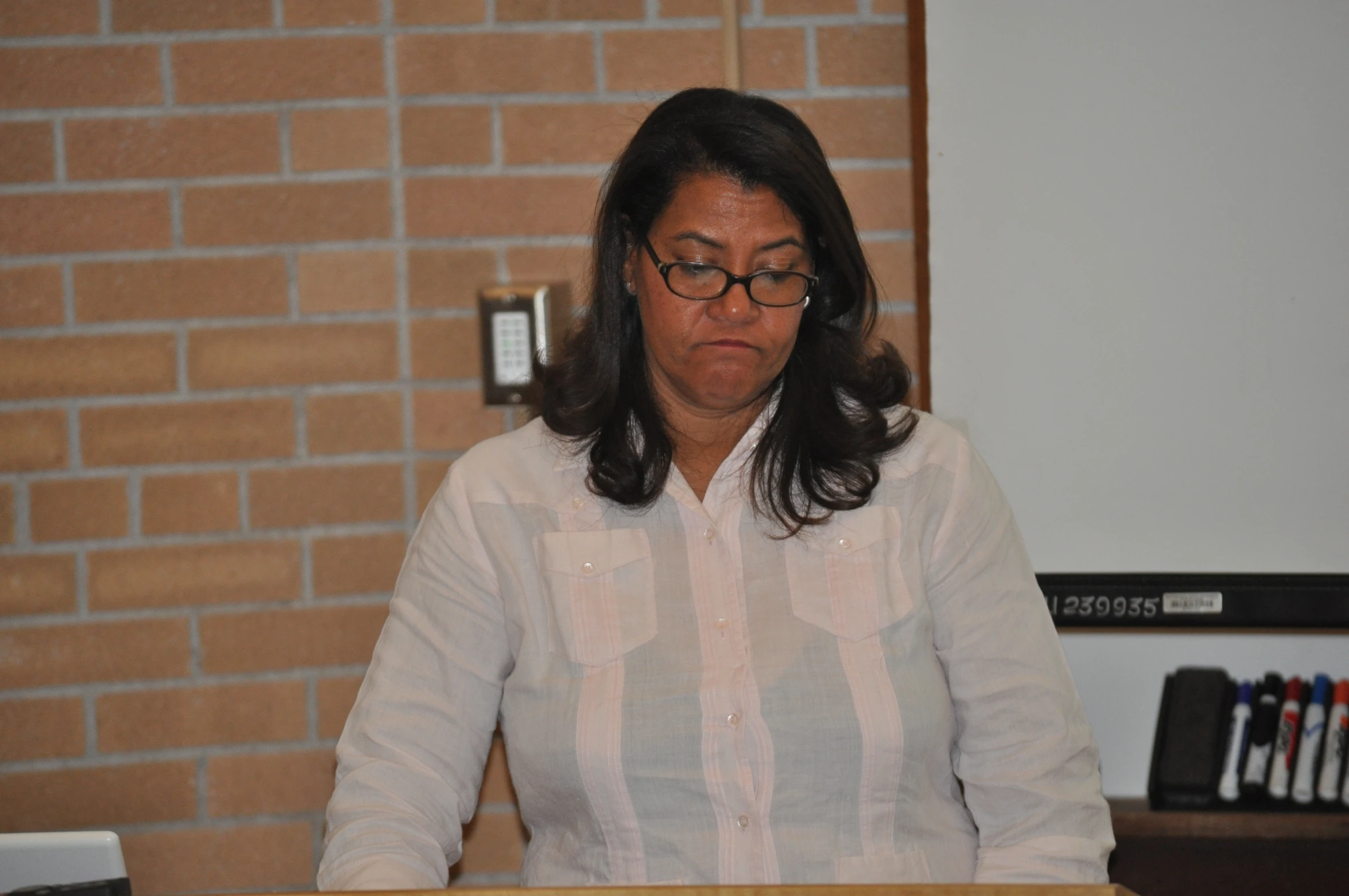 a woman sits behind a podium with a white blouse