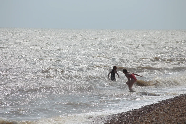 two surfers, one holding his surfboard, entering the waves