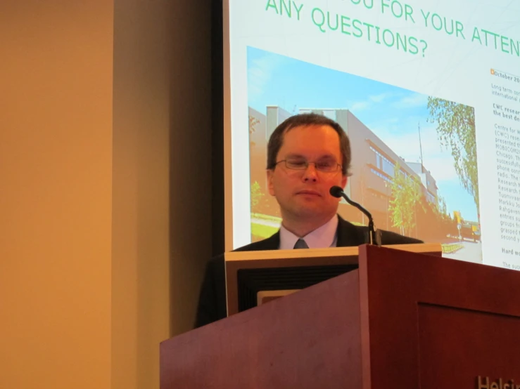 a man stands at a podium and looks off to the side