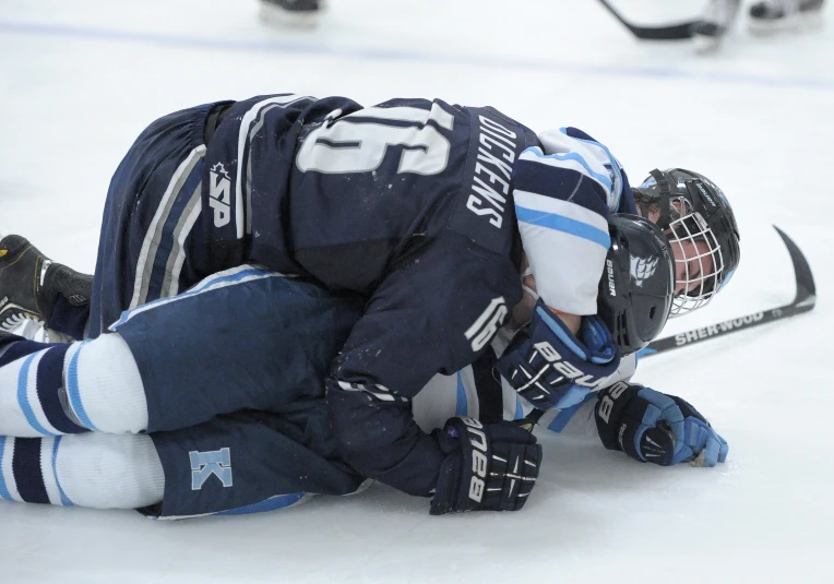 a hockey player who has fallen off of his helmet, kneeling down in the snow