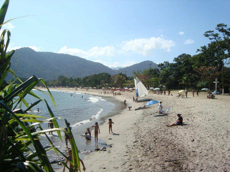 a beach filled with lots of people under a blue sky