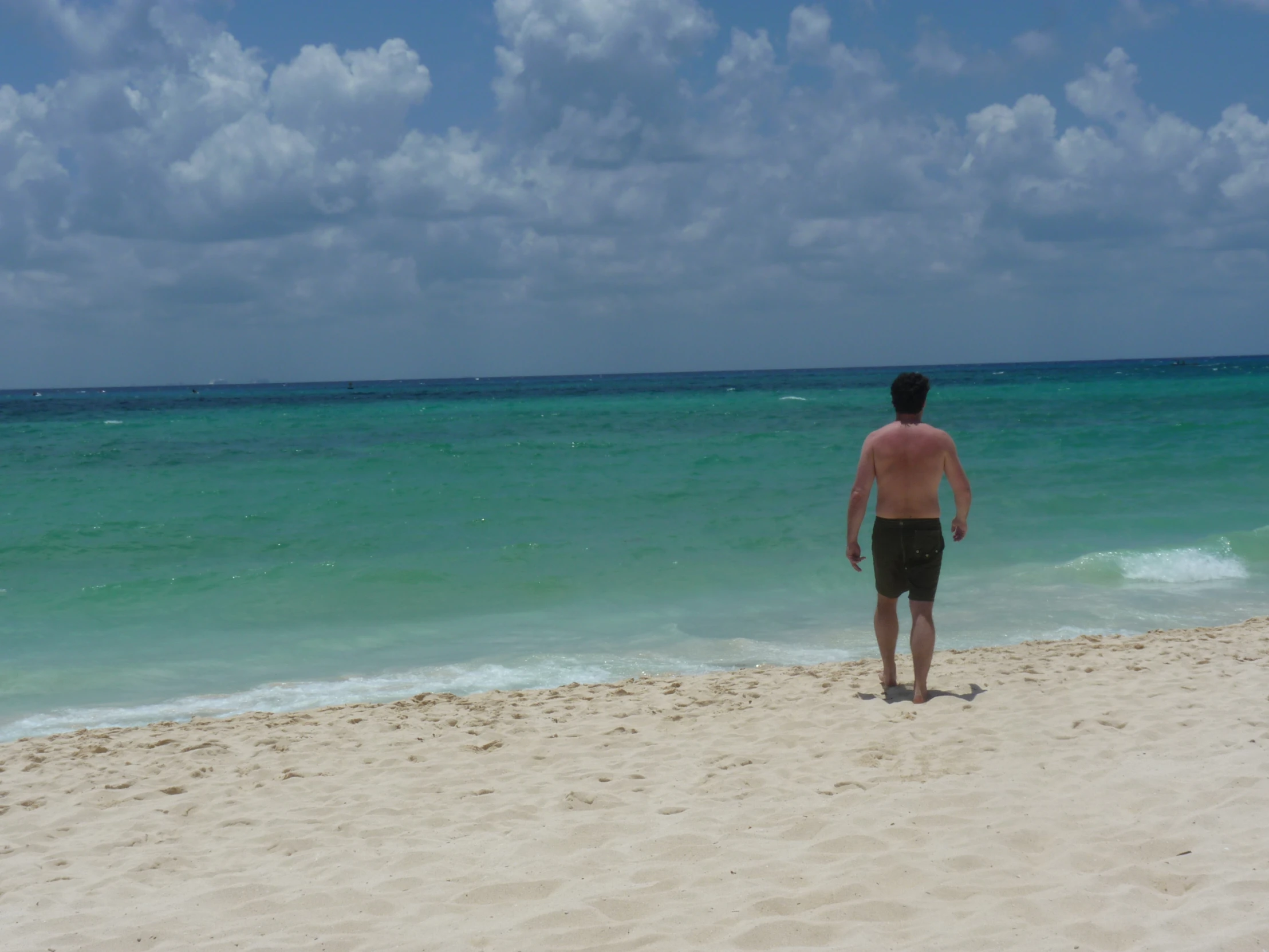 the man is standing alone at the beach watching the water