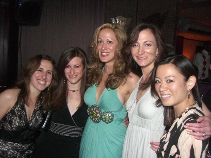 several women and one man pose together at a party