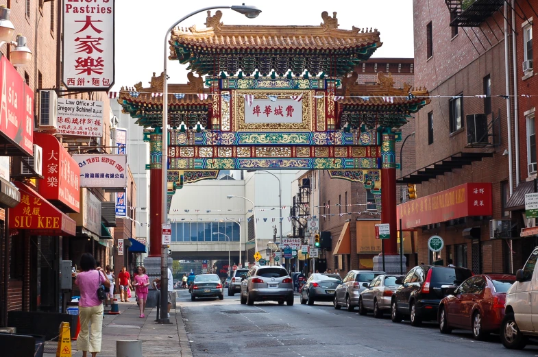 cars line the side of a street under an arch