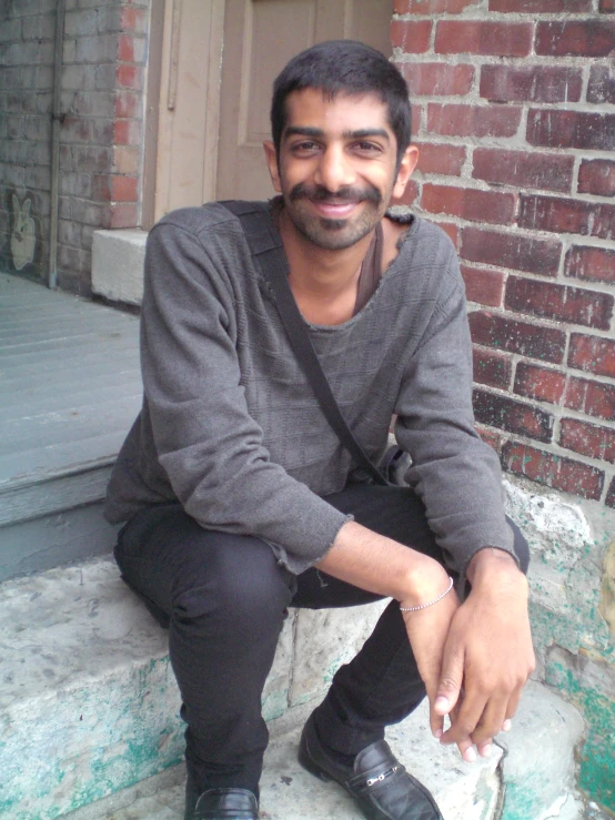 a smiling man is sitting on the steps