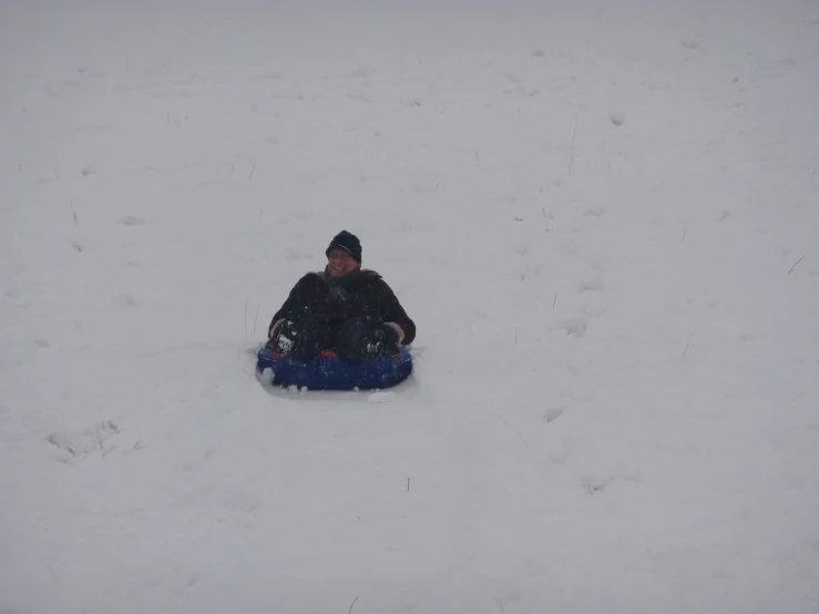 person snow sledding down hill next to snow