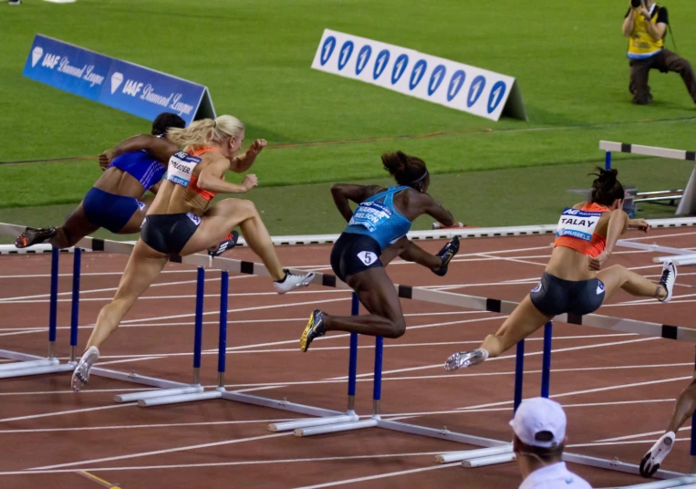 a couple of women jumping over an hurdle