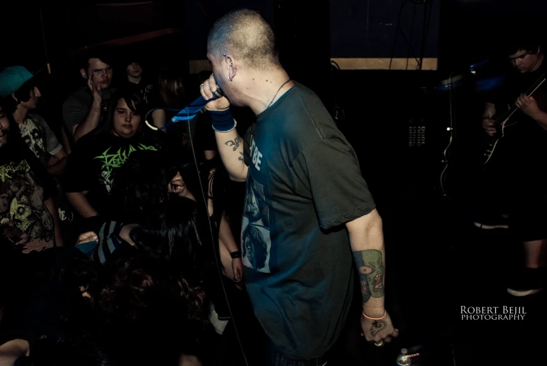 a man holding a microphone up to his ear and performing in front of a crowd