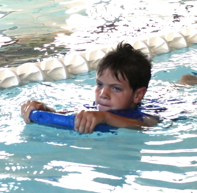 a boy with dark hair is swimming with a paddle