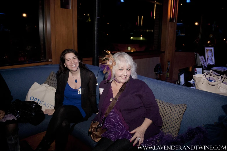 two women sitting on blue couches smiling at the camera