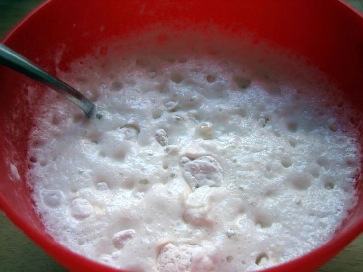 a red bowl with liquid in it is on the table