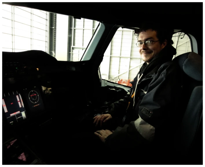 a man wearing glasses and sitting in the cockpit of an airplane