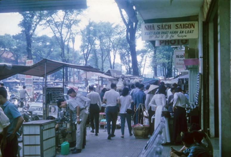 a group of people walk down a sidewalk in a market