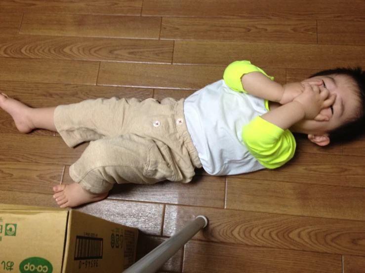 a small child lays on the floor with a pizza box