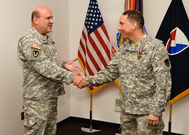 two people shake hands while wearing army uniforms