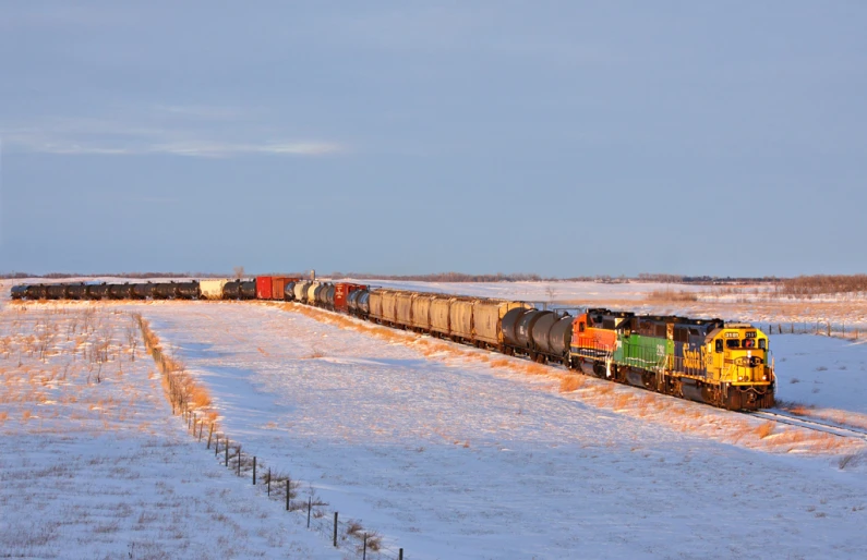 a train riding on a snowy track near a snowy field