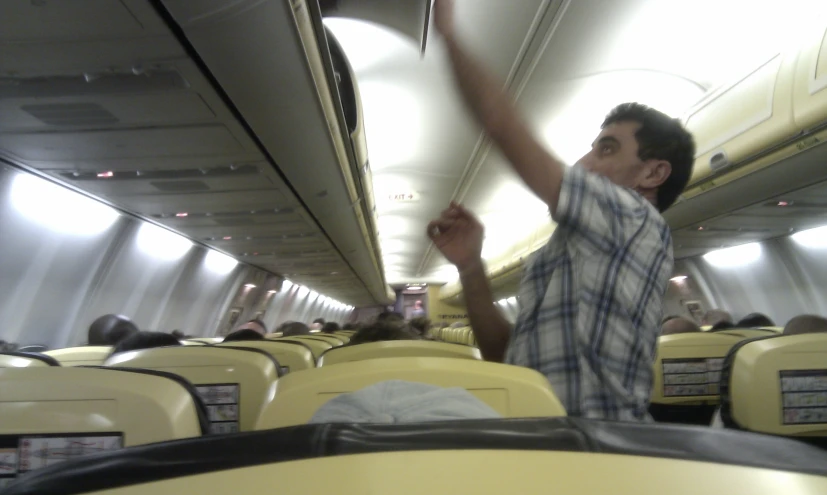 a young man waves and smiles while riding a plane