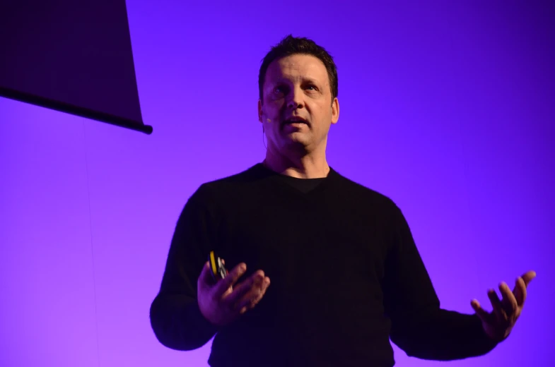 man in black shirt speaking while wearing yellow