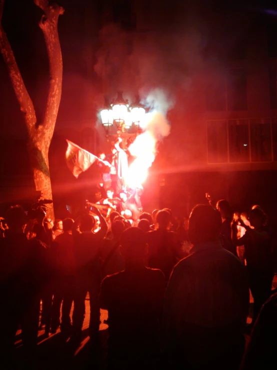 a crowd is watching a large bonfire on a street