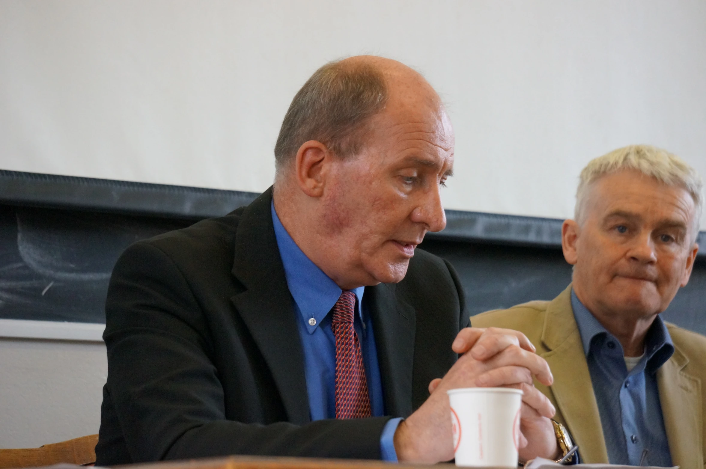 two people sitting at a table with cups in front of them