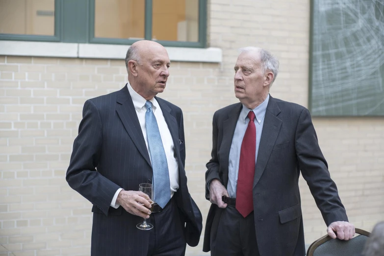 two men in suits stand next to each other