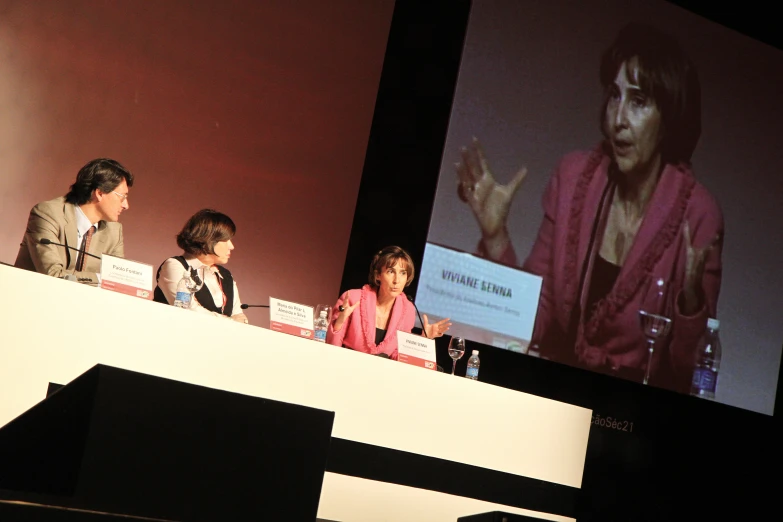 people on a stage in front of a screen with a man and woman talking to them