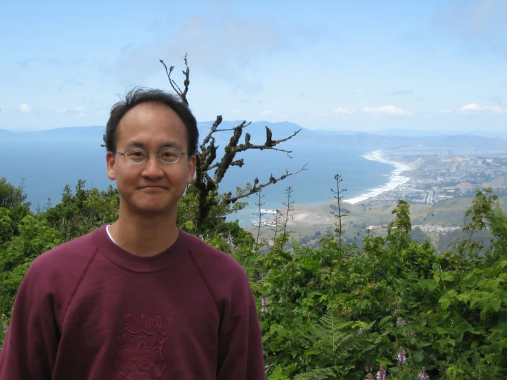 a man poses in front of the ocean in a forest