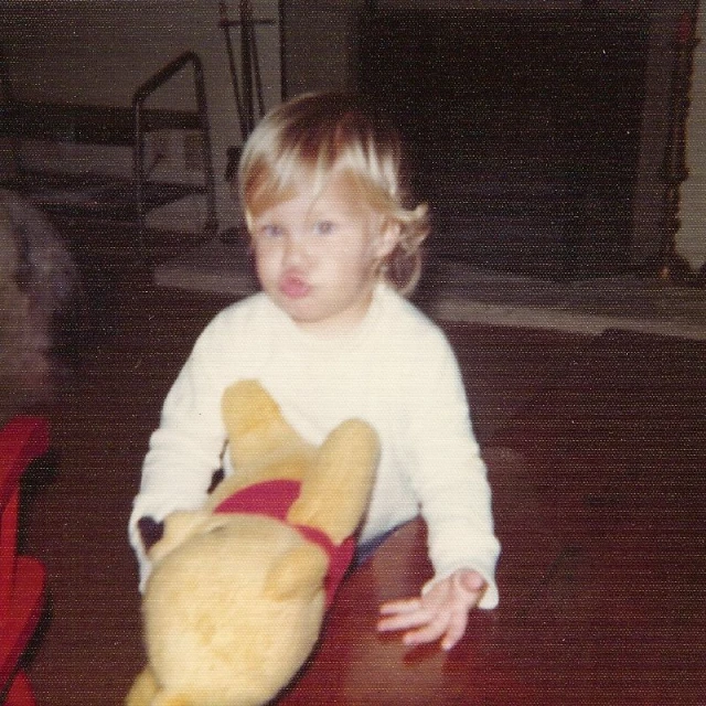 a little boy is sitting at a table holding a teddy bear