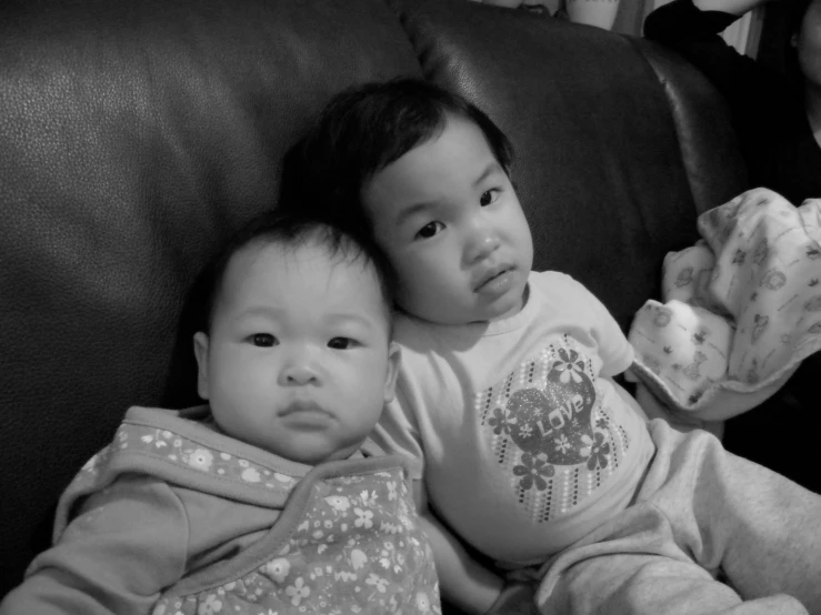 two babies laying on top of a sofa with their parents