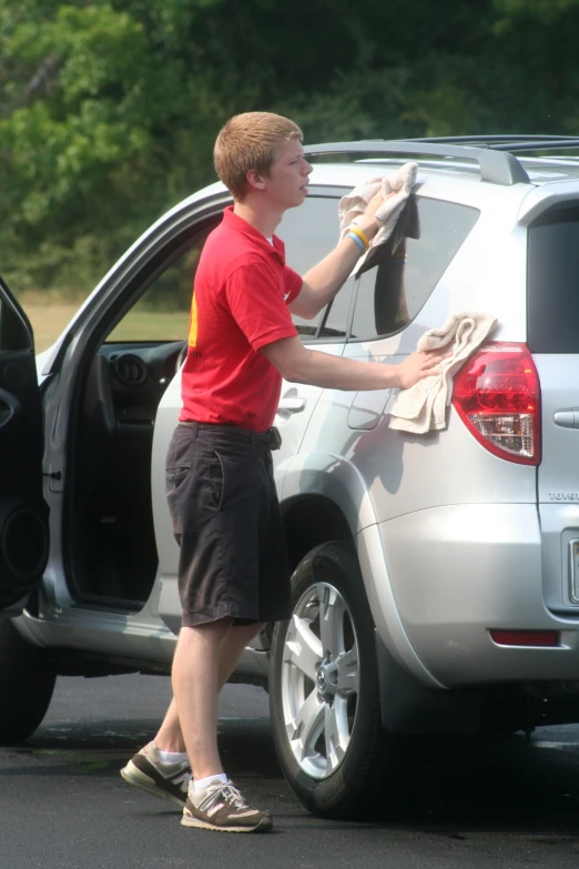 a man cleaning the inside of a silver vehicle