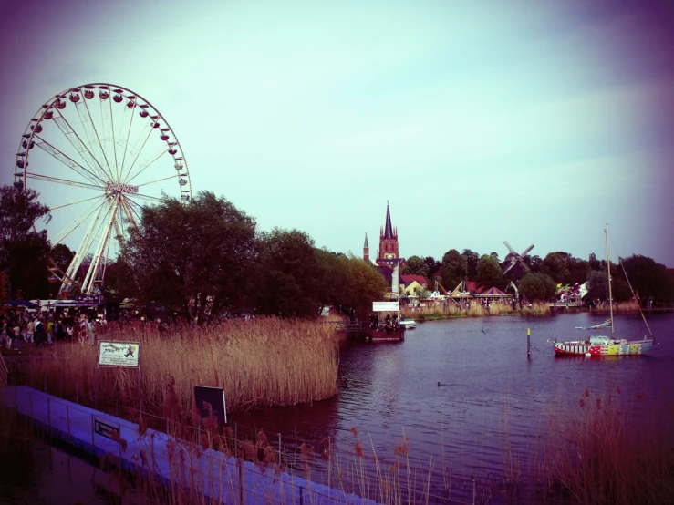 a large wheel is near the water in front of the ferris wheel