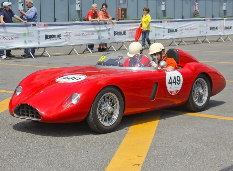 an old red race car on street with spectators