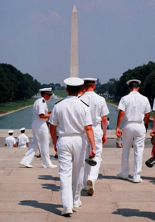 a group of sailors walking in front of a monument