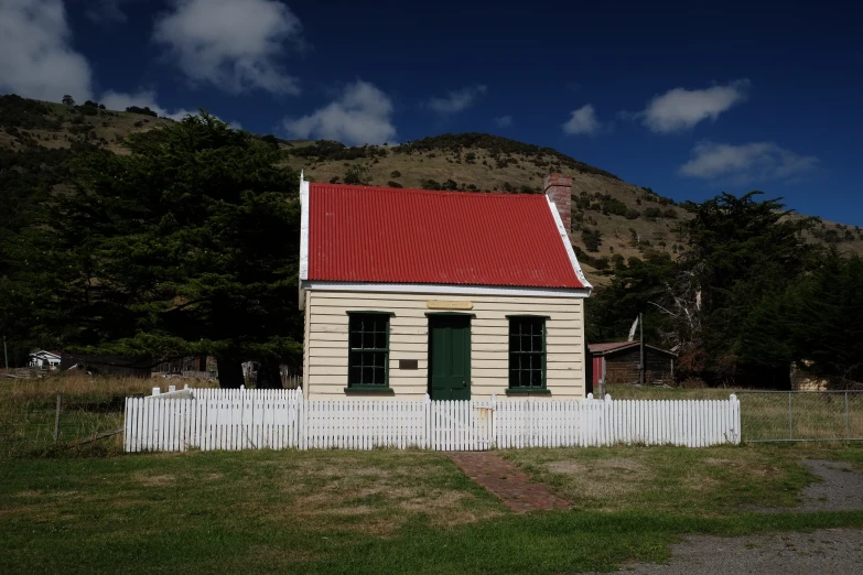 a building with a red roof next to a white fence