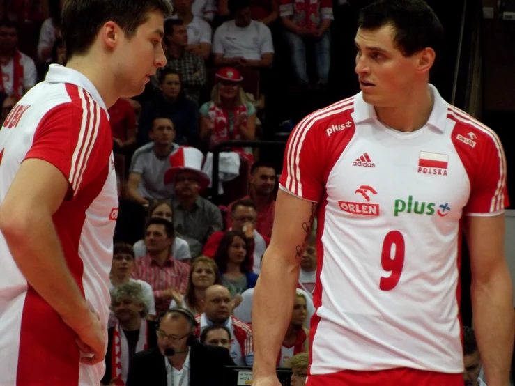 two men with red and white uniforms look toward each other