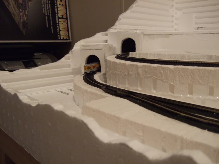 a large sculpture with train tracks and a clock on the side