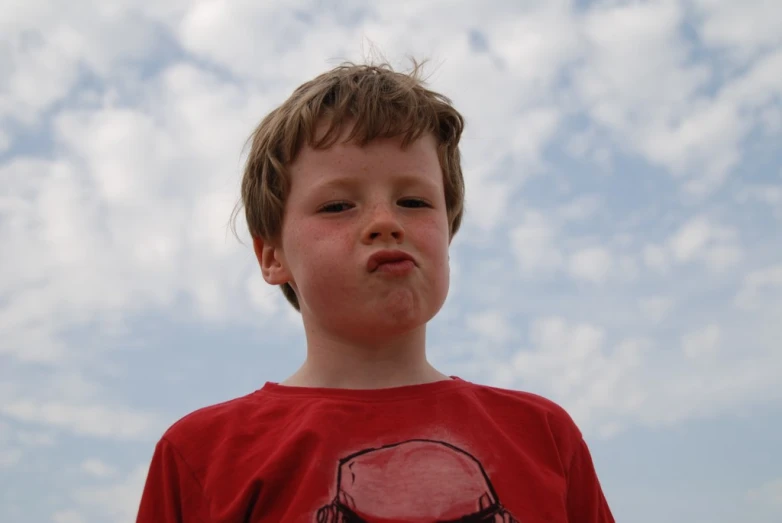 a little boy with a frisbee looking up at the sky