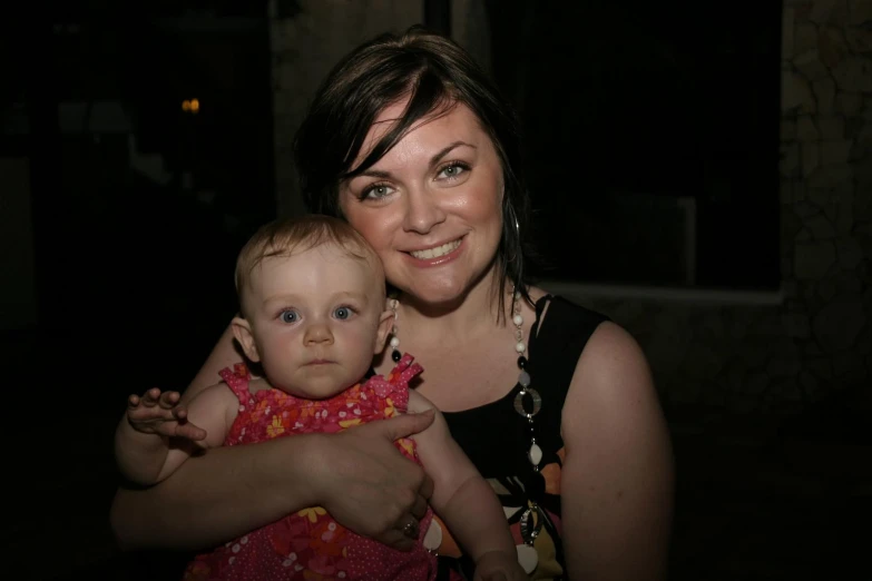 a woman holding a baby smiling at the camera