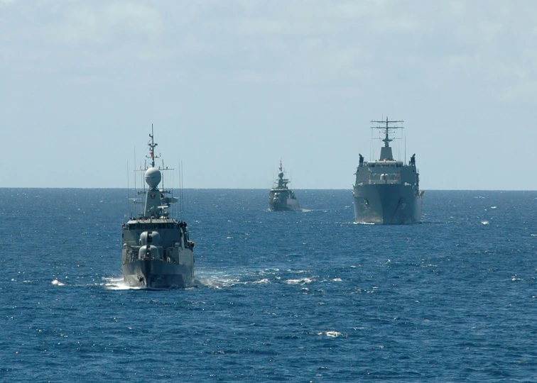 three ships out in the open water, one ship has its front end up