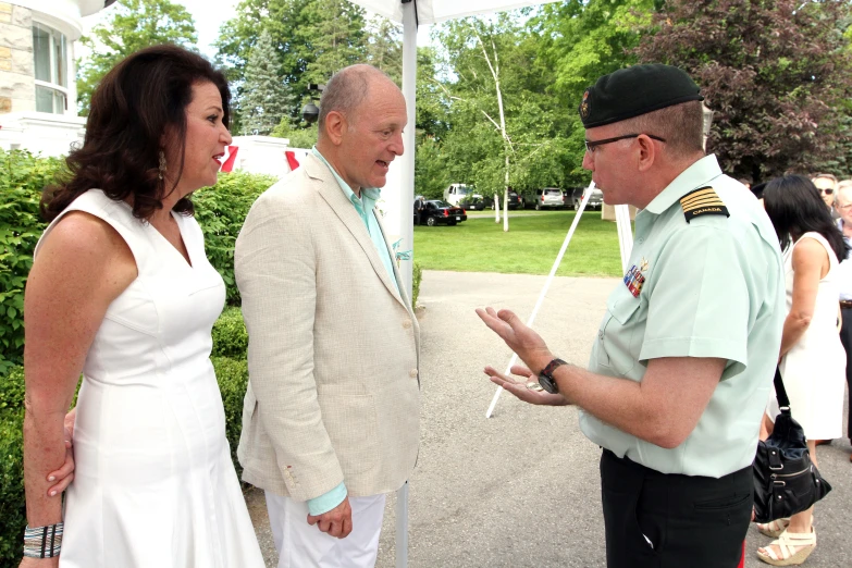 a woman in a white dress talking to an older man wearing a military uniform