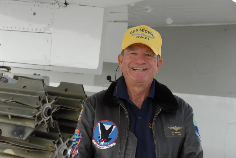 a man wearing a hat smiling while standing next to an airplane