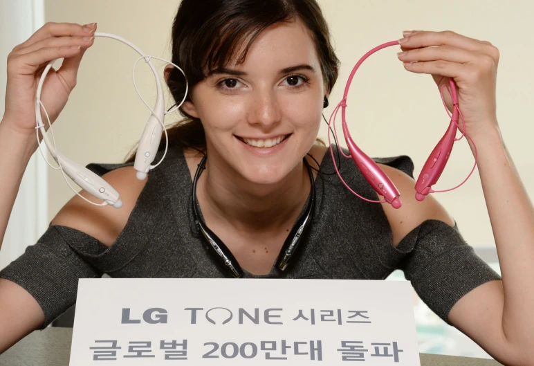 the woman is wearing pink and holding two pairs of headphones
