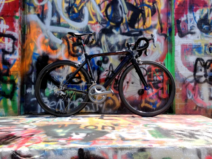 there is a bike that is leaning against a graffiti covered wall