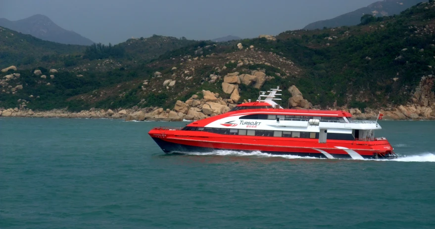 a boat in the middle of the ocean near a rocky shoreline