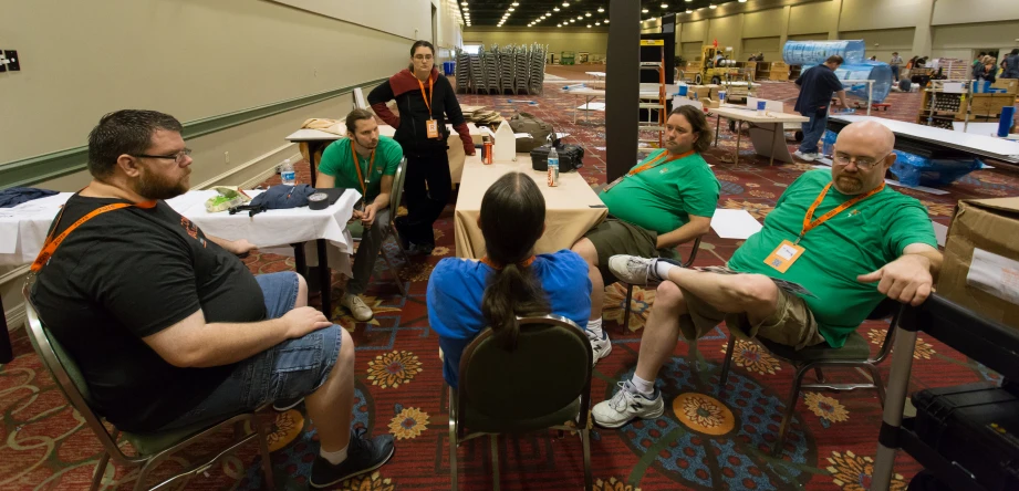 people sitting at tables in large room with white clothed walls