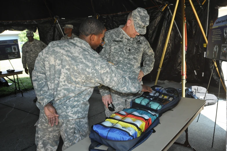 two men in uniforms are preparing bags on a table